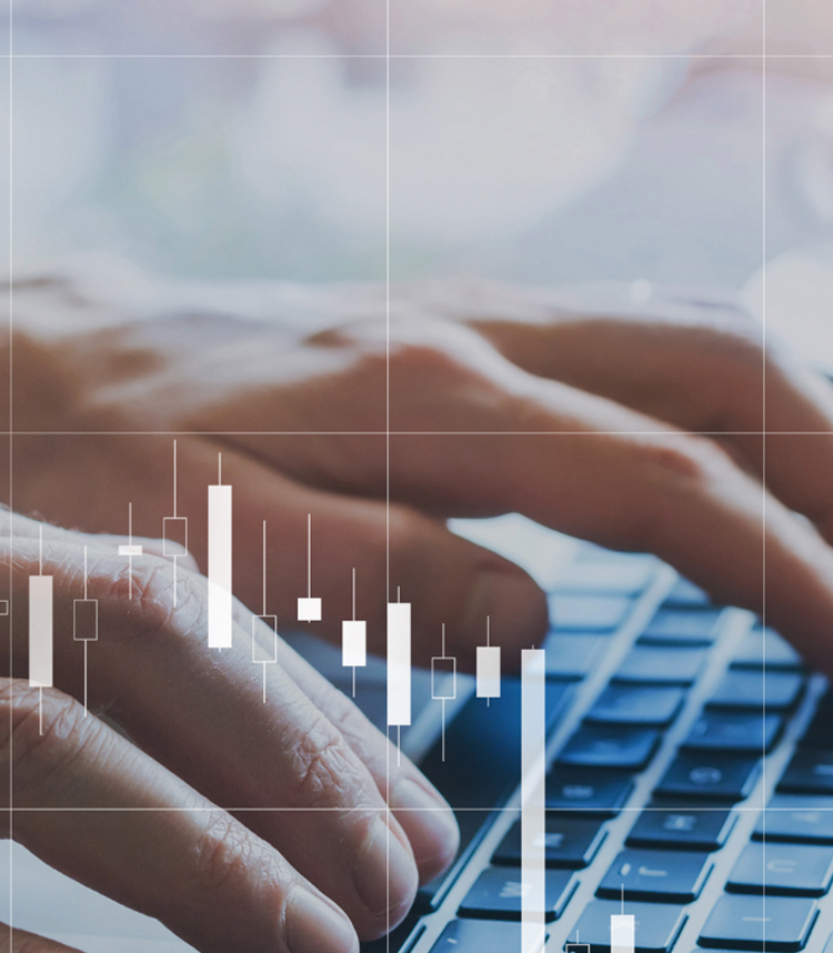 Close-up of hands typing on a keyboard with financial candlestick charts overlayed.